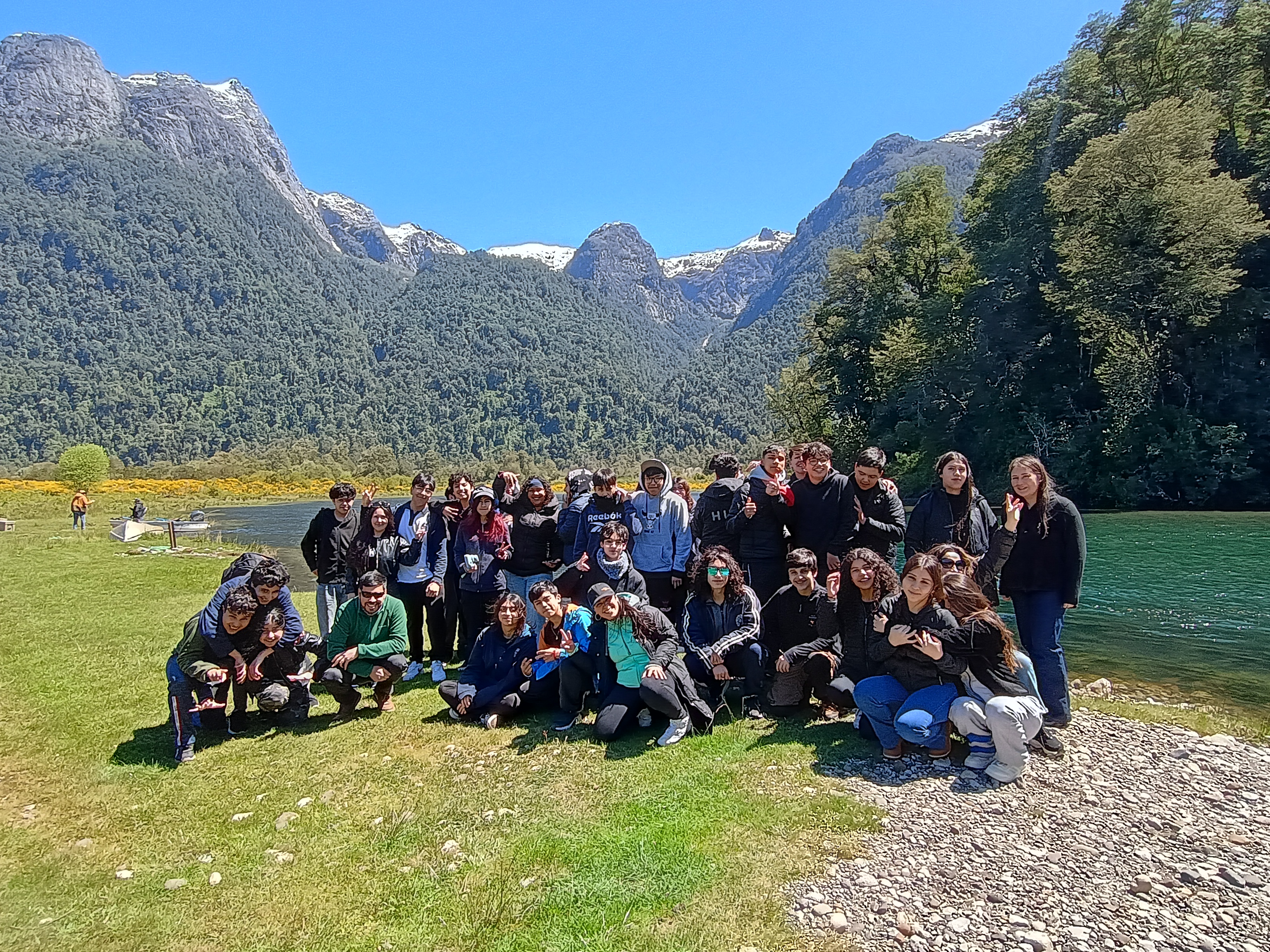 Estudiantes del liceo posando en grupo junto a un lago y montañas durante una salida pedagógica