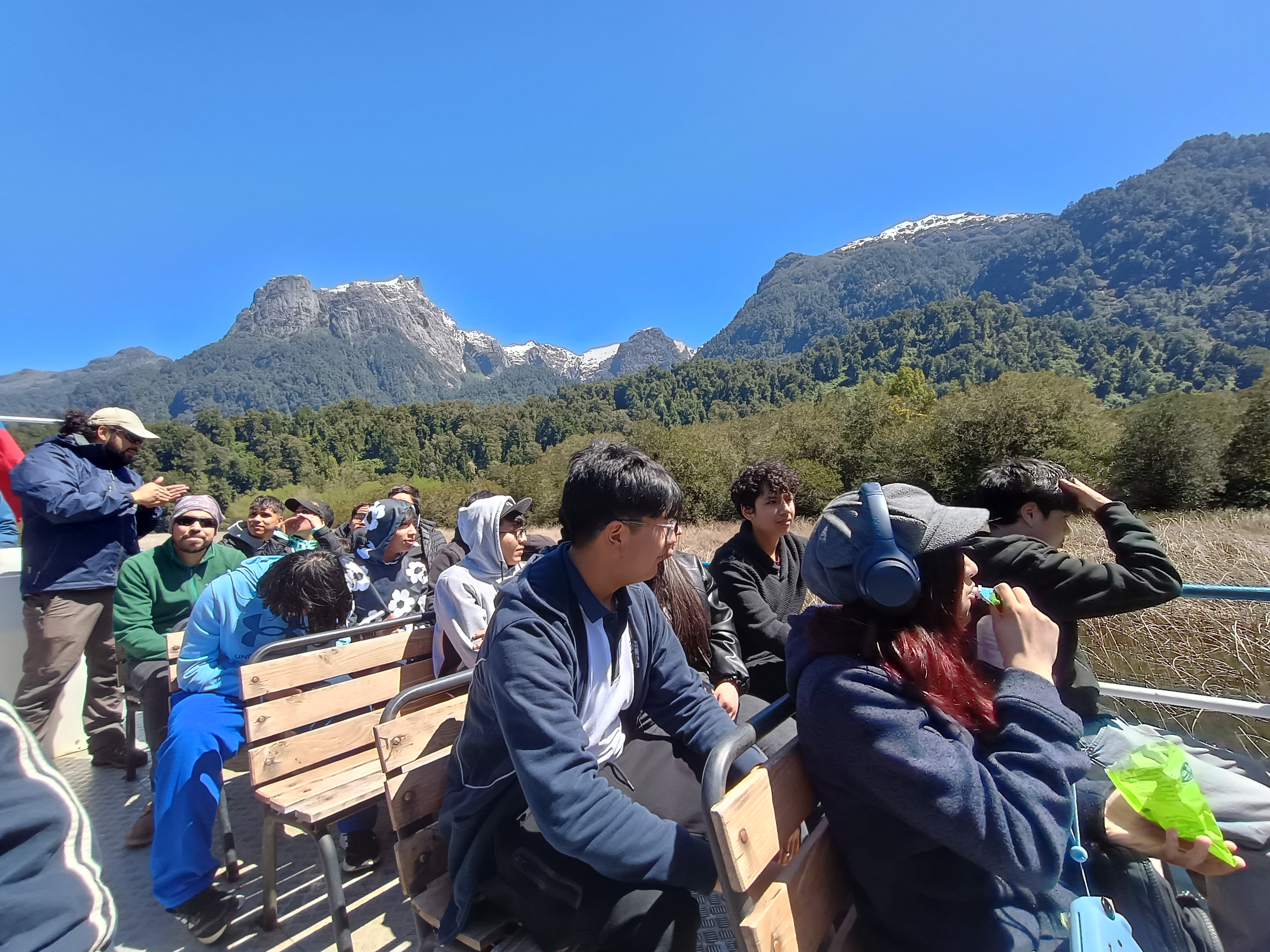 Estudiantes del liceo en una embarcación observando el paisaje de montañas durante una salida pedagógica