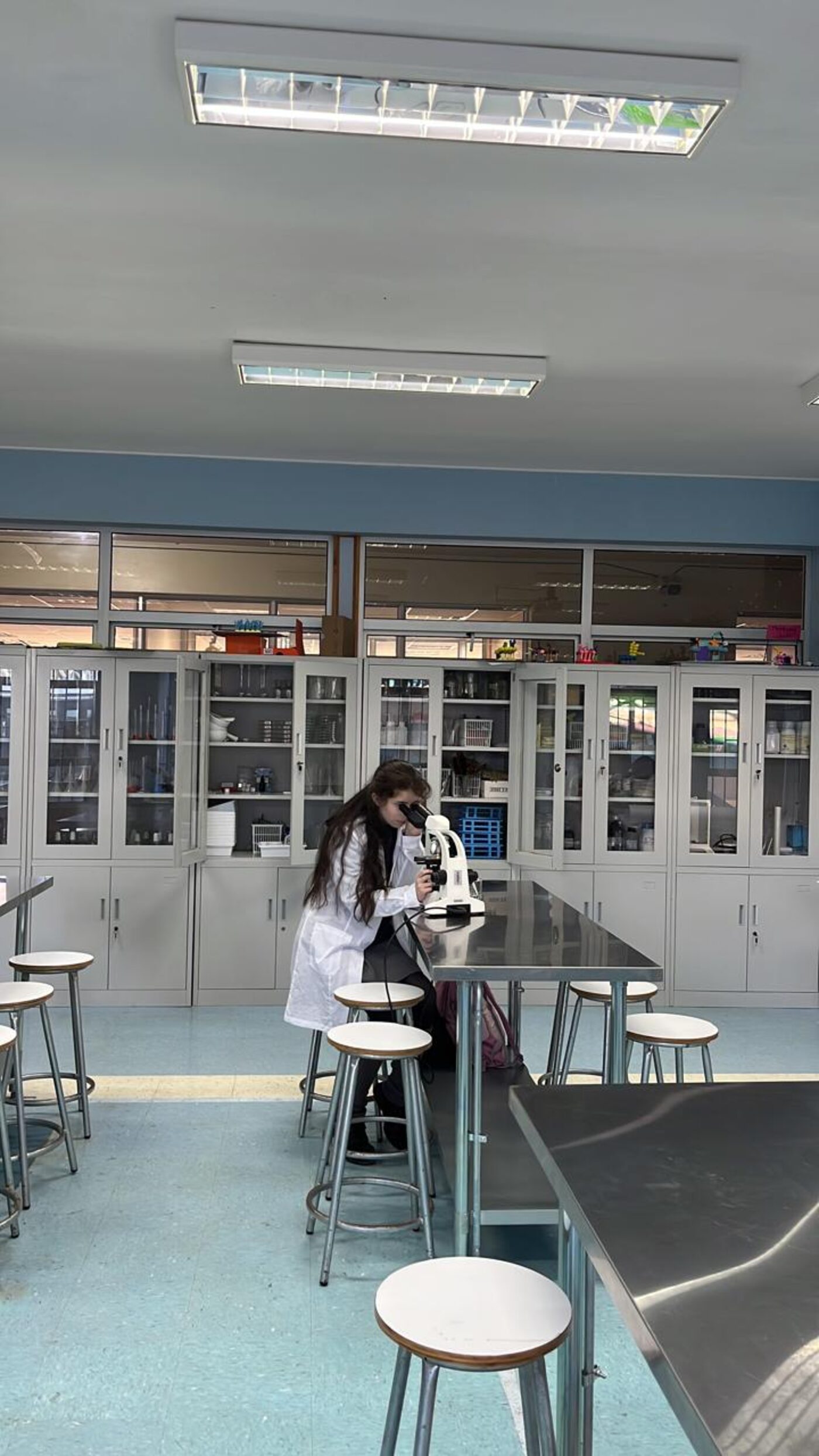 Estudiante trabajando con microscopio en la sala de laboratorio del liceo
