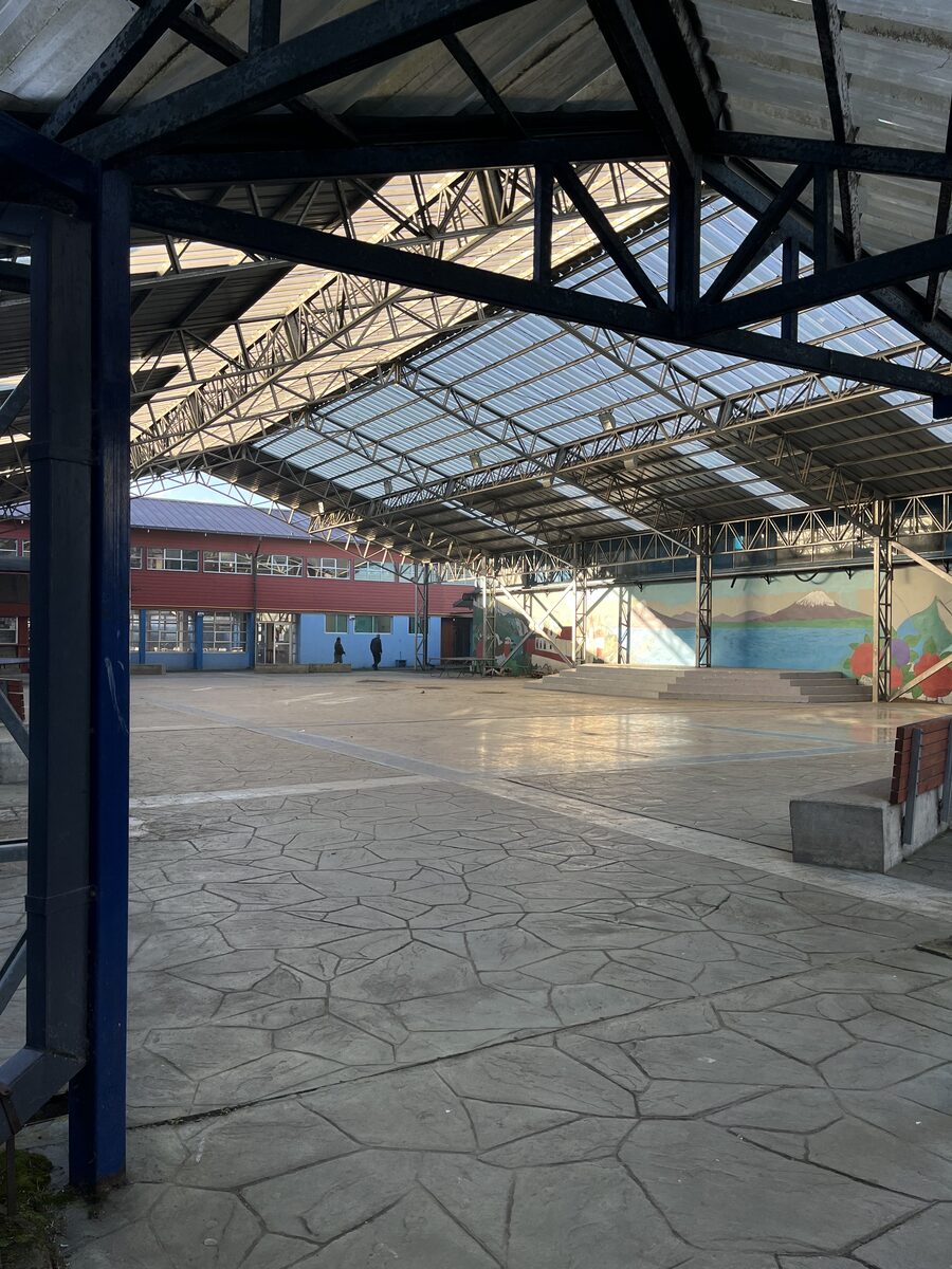 Patio techado del liceo con murales y vista al edificio principal