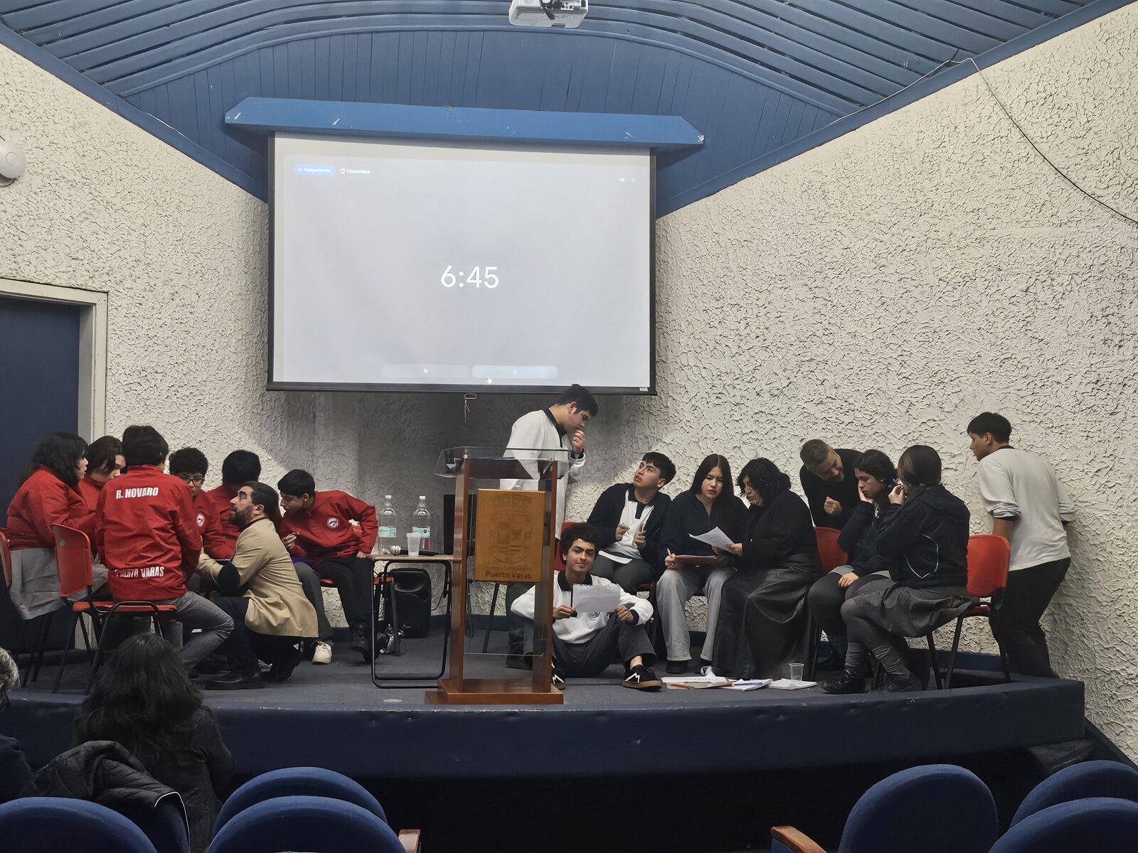 Equipos de debate reunidos en el escenario del auditorio durante una ronda